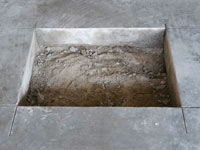 Creating the hole in the garage slab floor during the wall anchor installation in Clarence.