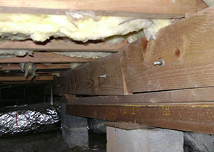 A sagging crawl space with concrete supports and wooden shimming a East Amherst crawl space