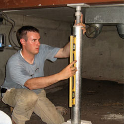 A contractor in Depew installing a crawl space jack post.