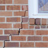 long jagged cracks starting at the corner of a window along a brick wall on a Angola home
