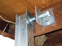 Securing the i-beam system to the top of the floor joist in a foundation wall repair in Orchard Park.